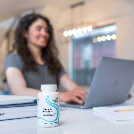image of woman working at computer next to a bottle of Dopamine Nutrients