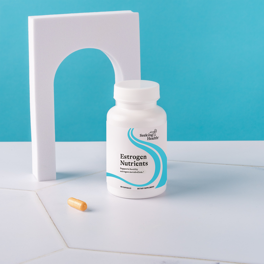 Bottle of Estrogen Nutrients with a supplement capsule on a white surface against a blue background