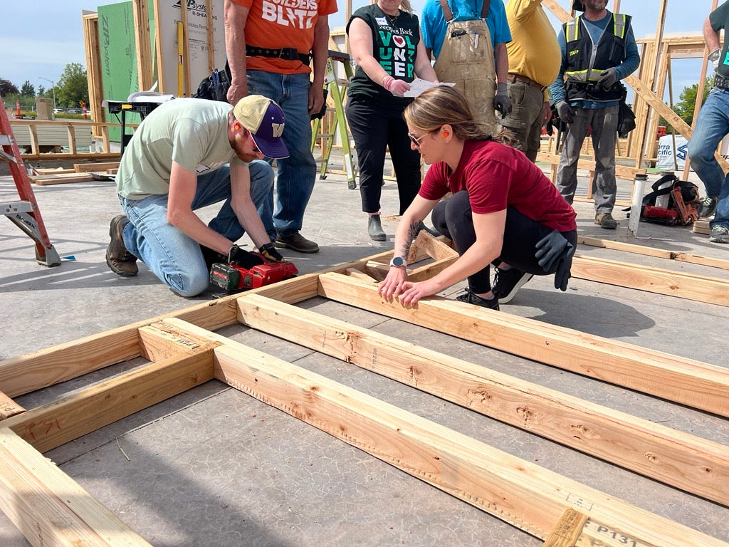 People working on a construction site assembling wooden beams.