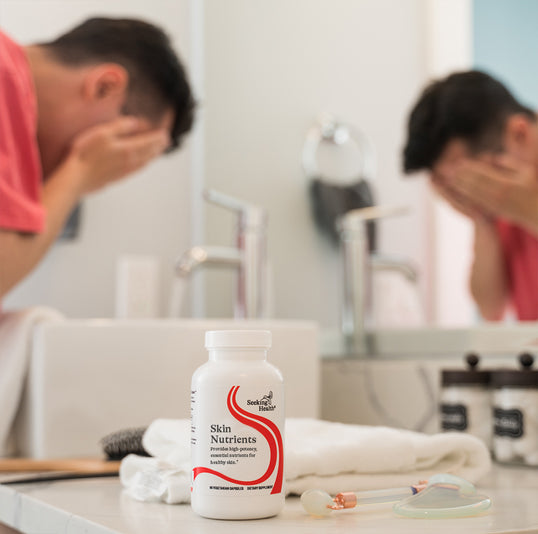 A man washing his face behind a bottle of Skin Nutrients
